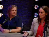 two women having a conversation at a table next to a microphone