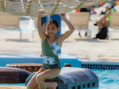 child uses rope ladder above pool